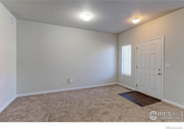 entryway with carpet flooring and a textured ceiling