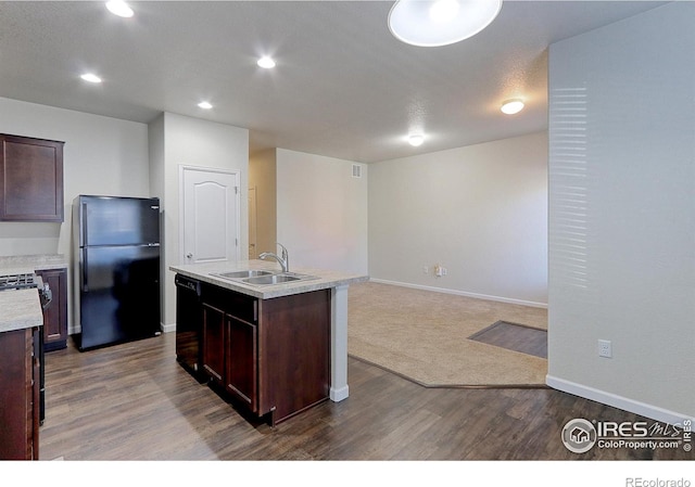 kitchen with dark brown cabinetry, sink, black appliances, light hardwood / wood-style floors, and an island with sink