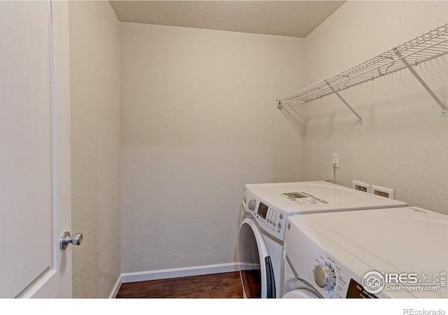 clothes washing area with a textured ceiling, separate washer and dryer, and dark wood-type flooring