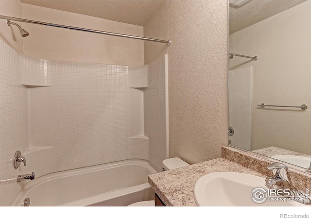 full bathroom with vanity, tiled shower / bath combo, a textured ceiling, and toilet