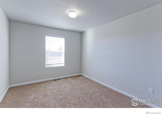 carpeted spare room with a textured ceiling