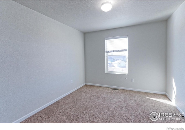 carpeted spare room featuring a textured ceiling