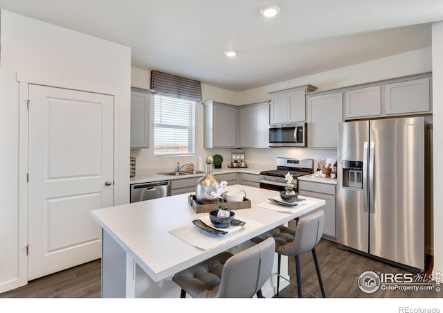 kitchen with a breakfast bar area, a center island, dark hardwood / wood-style floors, and appliances with stainless steel finishes