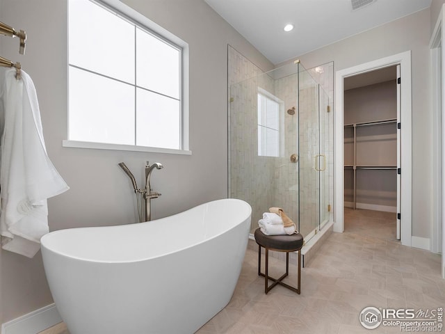 full bathroom with a spacious closet, baseboards, recessed lighting, a stall shower, and a soaking tub