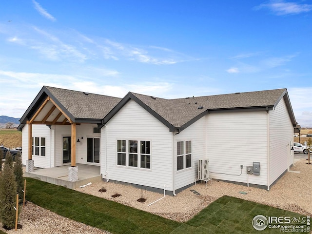 rear view of house with ac unit, roof with shingles, and a patio area