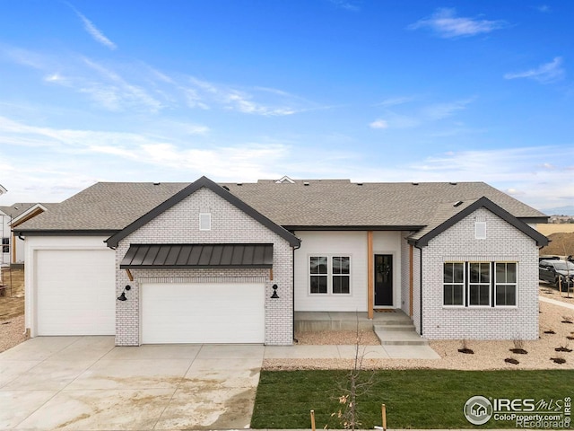 modern farmhouse style home with brick siding, a standing seam roof, concrete driveway, and a garage