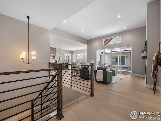 hall featuring baseboards, recessed lighting, an upstairs landing, light wood-type flooring, and a chandelier