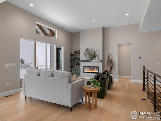 living room with light wood-type flooring and a high ceiling