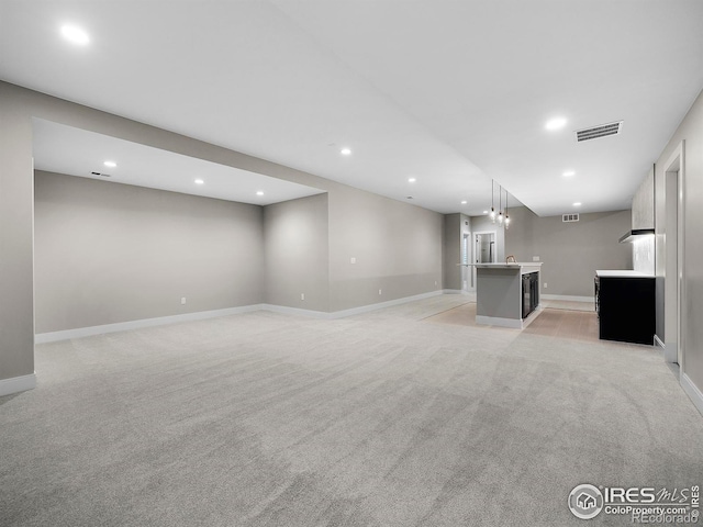 unfurnished living room with light carpet, visible vents, recessed lighting, and baseboards