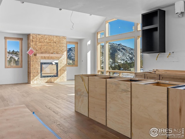 kitchen with a mountain view, a fireplace, wood-type flooring, and vaulted ceiling