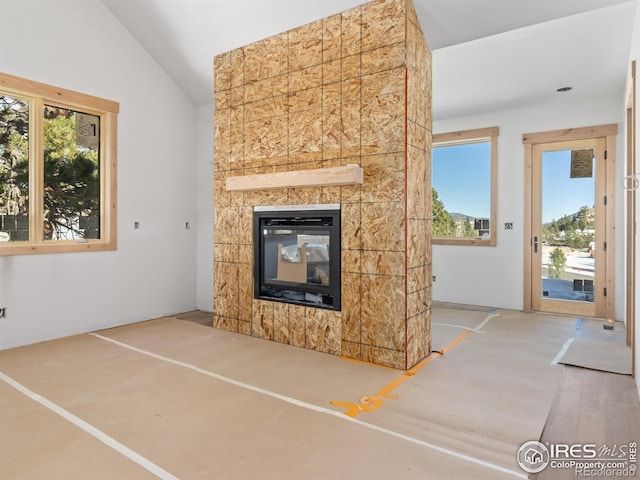 unfurnished living room featuring wood-type flooring, plenty of natural light, lofted ceiling, and a tiled fireplace