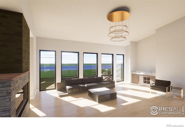 living room featuring a notable chandelier, a stone fireplace, a water view, and light hardwood / wood-style flooring