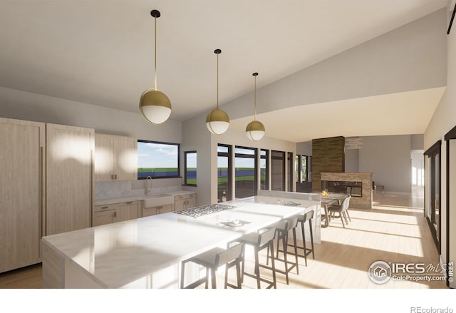 kitchen with a center island, stainless steel gas cooktop, a stone fireplace, pendant lighting, and light wood-type flooring