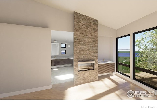 unfurnished living room featuring a fireplace, plenty of natural light, vaulted ceiling, and light hardwood / wood-style flooring