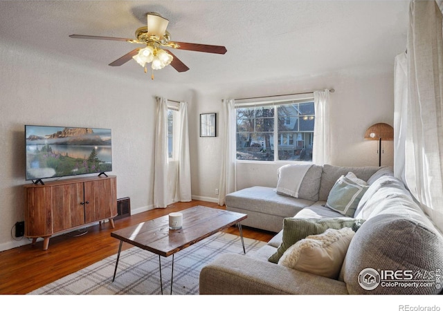 living room with a textured ceiling, light wood-type flooring, and ceiling fan