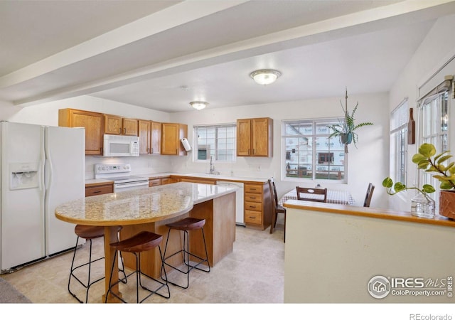 kitchen featuring a kitchen breakfast bar, white appliances, and a kitchen island