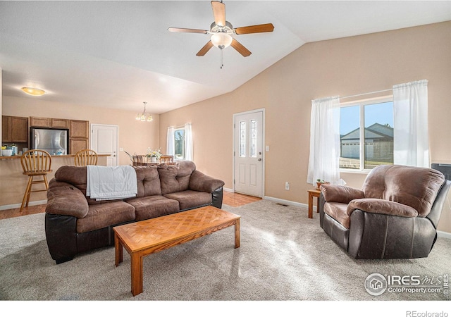 living room with ceiling fan with notable chandelier, light colored carpet, and lofted ceiling