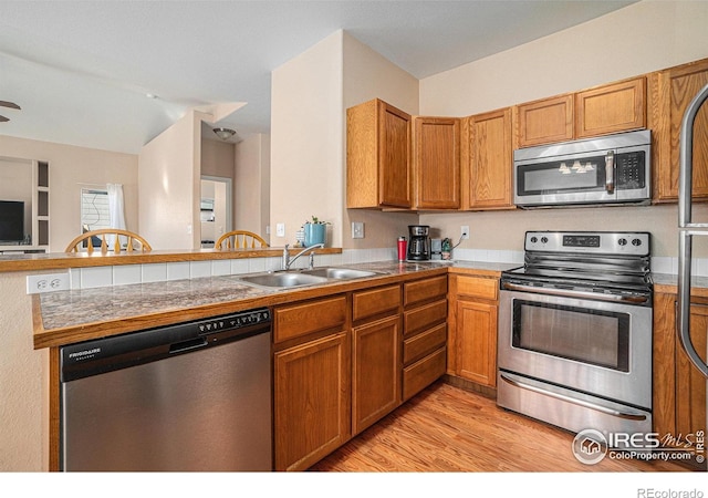 kitchen featuring ceiling fan, sink, light hardwood / wood-style flooring, kitchen peninsula, and appliances with stainless steel finishes