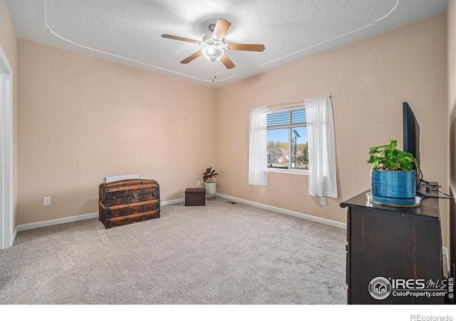 sitting room featuring carpet flooring, ceiling fan, and a textured ceiling