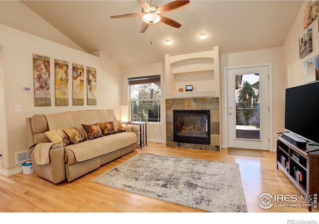 living room featuring a tile fireplace, ceiling fan, wood-type flooring, and lofted ceiling