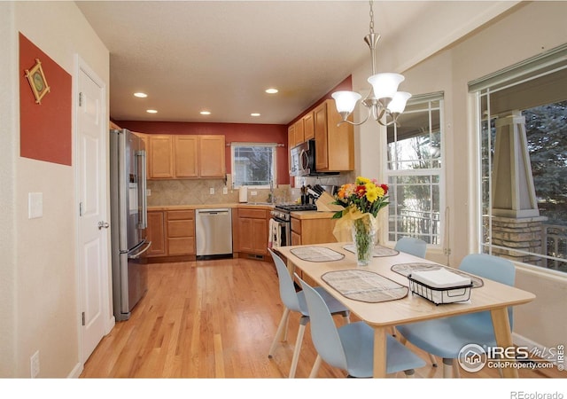 kitchen featuring backsplash, an inviting chandelier, hanging light fixtures, light hardwood / wood-style flooring, and stainless steel appliances