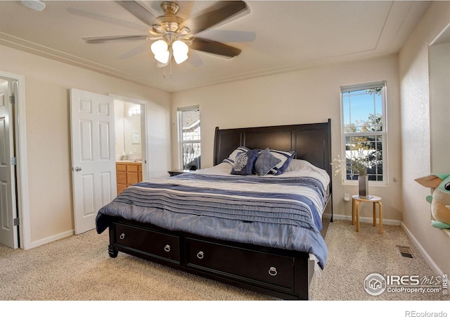 carpeted bedroom with ensuite bath and ceiling fan