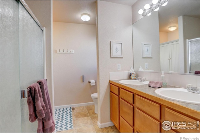 bathroom with tile patterned floors, vanity, a shower with shower door, and toilet