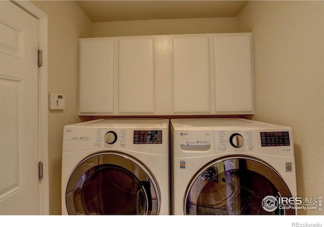 clothes washing area featuring washer and clothes dryer and cabinets