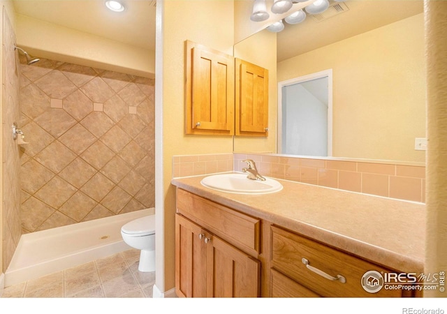 bathroom with vanity, toilet, and a tile shower