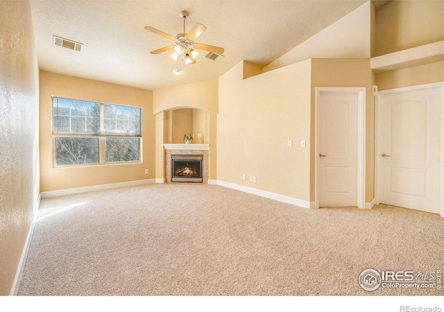 unfurnished living room featuring carpet, lofted ceiling, ceiling fan, a textured ceiling, and a tiled fireplace