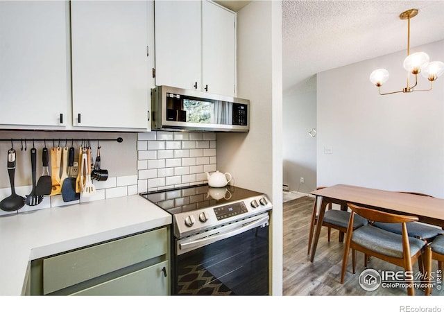 kitchen with tasteful backsplash, appliances with stainless steel finishes, light countertops, white cabinetry, and pendant lighting