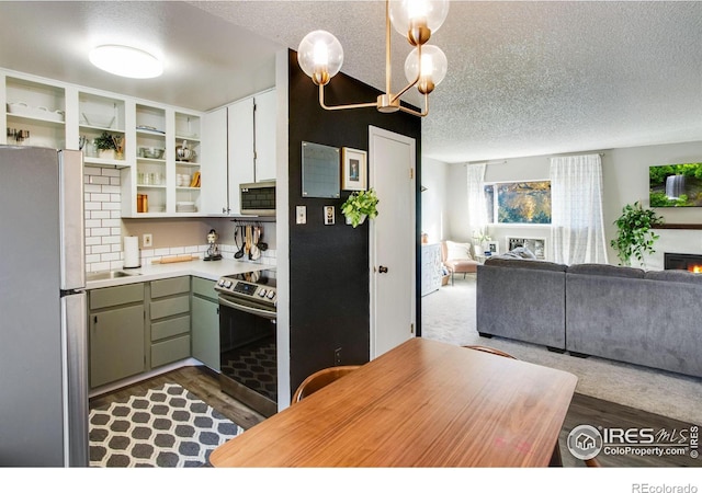 kitchen with appliances with stainless steel finishes, open floor plan, light countertops, a textured ceiling, and green cabinetry