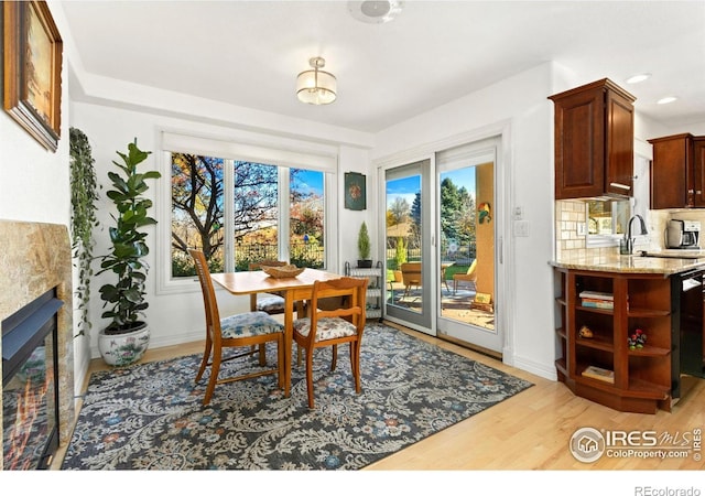 dining area with light hardwood / wood-style floors, sink, and a tiled fireplace