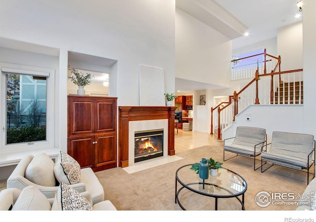 378 High Pointe Dr, Fort Collins, CO 80525 - living room with stairway, light carpet, a fireplace with flush hearth, and a towering ceiling