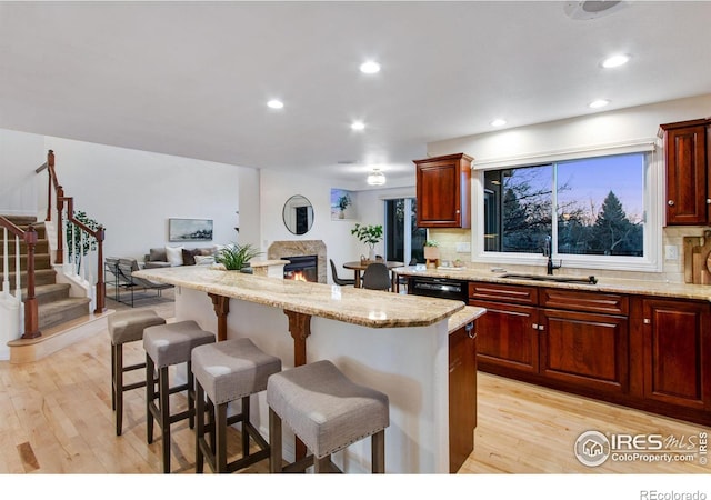 378 High Pointe Dr, Fort Collins, CO 80525 - kitchen featuring a sink, light wood finished floors, a kitchen bar, a lit fireplace, and recessed lighting