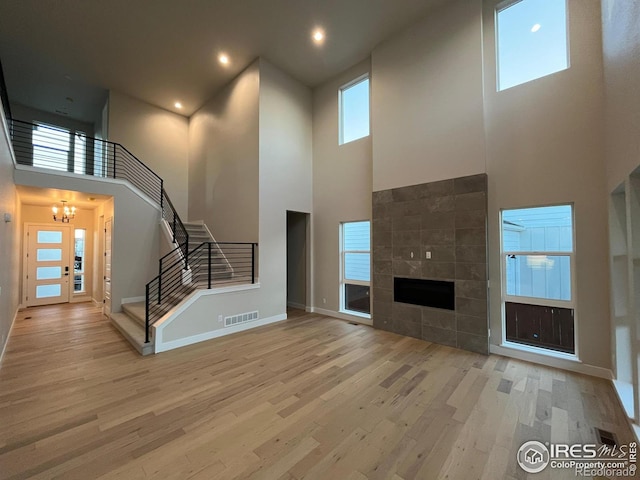 unfurnished living room with light hardwood / wood-style floors, a towering ceiling, and a wealth of natural light