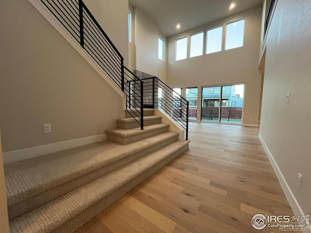 stairs with hardwood / wood-style flooring and a towering ceiling