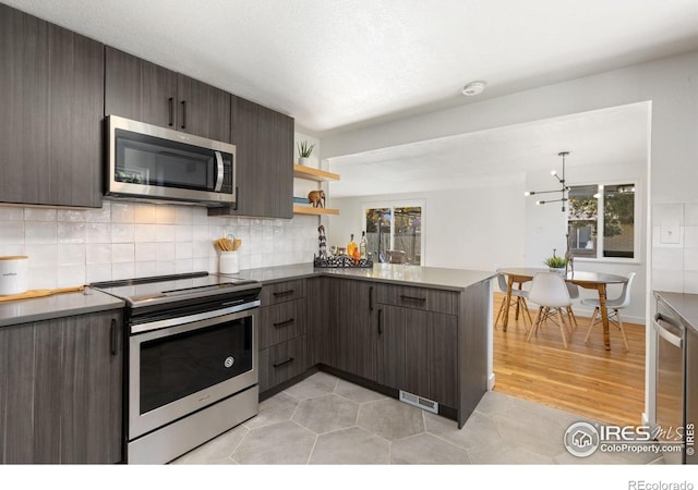 kitchen featuring kitchen peninsula, dark brown cabinetry, stainless steel appliances, and light wood-type flooring