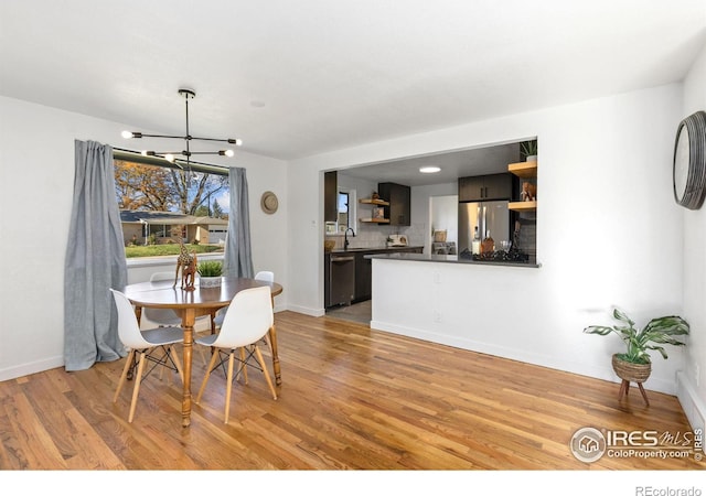 dining space with a chandelier, sink, and light hardwood / wood-style flooring