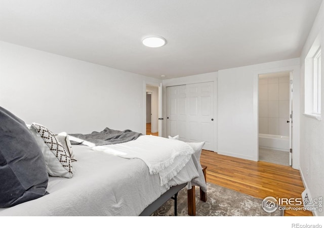 bedroom featuring hardwood / wood-style flooring, connected bathroom, and a closet