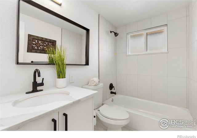 full bathroom featuring vanity, tiled shower / bath, and toilet