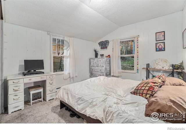 carpeted bedroom with a textured ceiling, vaulted ceiling, and wood walls