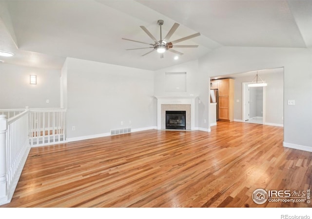 unfurnished living room featuring lofted ceiling, ceiling fan, light wood-type flooring, and a fireplace