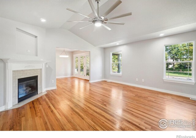 unfurnished living room with a tile fireplace, ceiling fan, light hardwood / wood-style floors, and vaulted ceiling