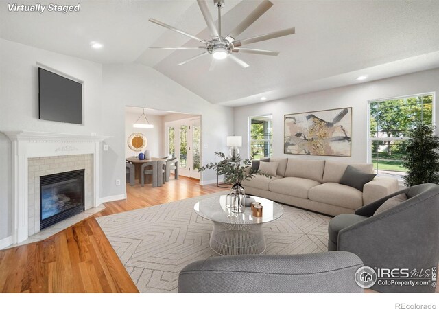 living room with a fireplace, vaulted ceiling, light hardwood / wood-style flooring, and ceiling fan