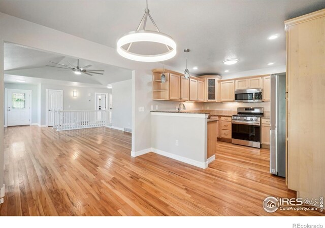 kitchen with appliances with stainless steel finishes, light brown cabinetry, light hardwood / wood-style flooring, hanging light fixtures, and lofted ceiling