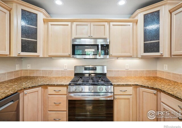 kitchen featuring light brown cabinets, stainless steel appliances, and light stone counters