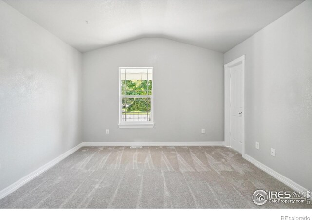 unfurnished room with light colored carpet and vaulted ceiling