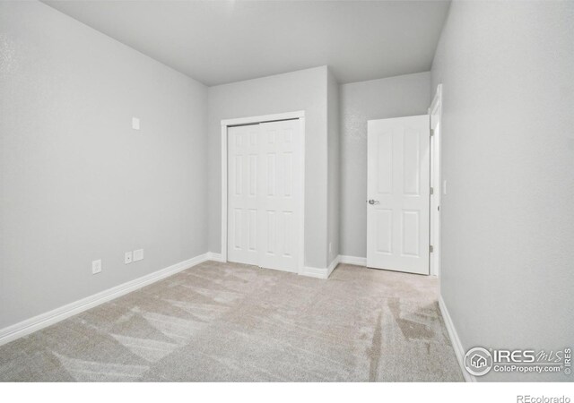 unfurnished bedroom with a closet and light colored carpet