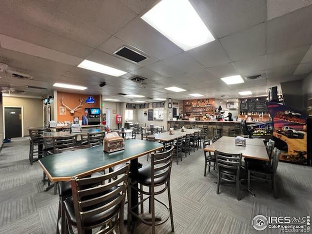 carpeted dining area with a paneled ceiling